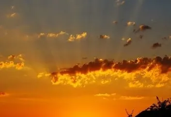 A sunset with clouds in the sky and a bird flying above.