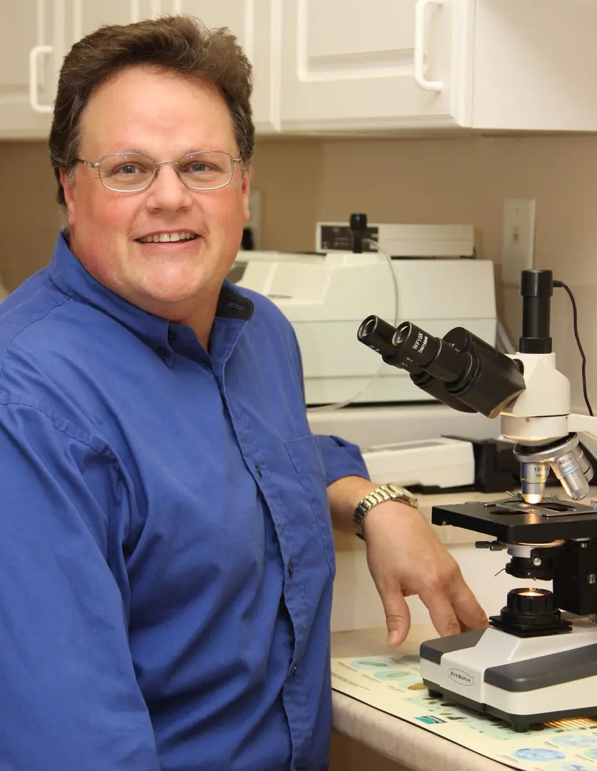 A man standing in front of a microscope.