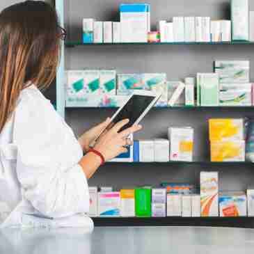 A woman is using her tablet in front of the shelves.